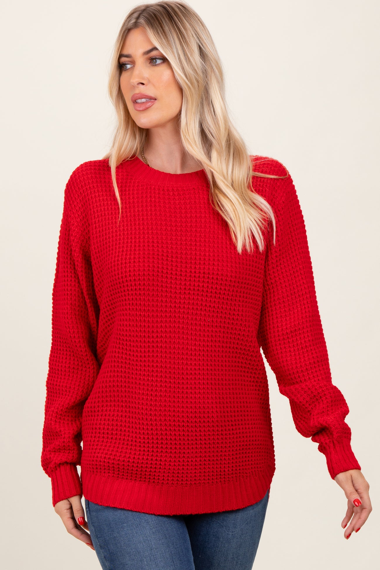 woman wearing a bright red oversized knitted sweater with long sleeves and a round neckline