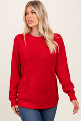 woman wearing a bright red oversized knitted sweater with long sleeves and a round neckline