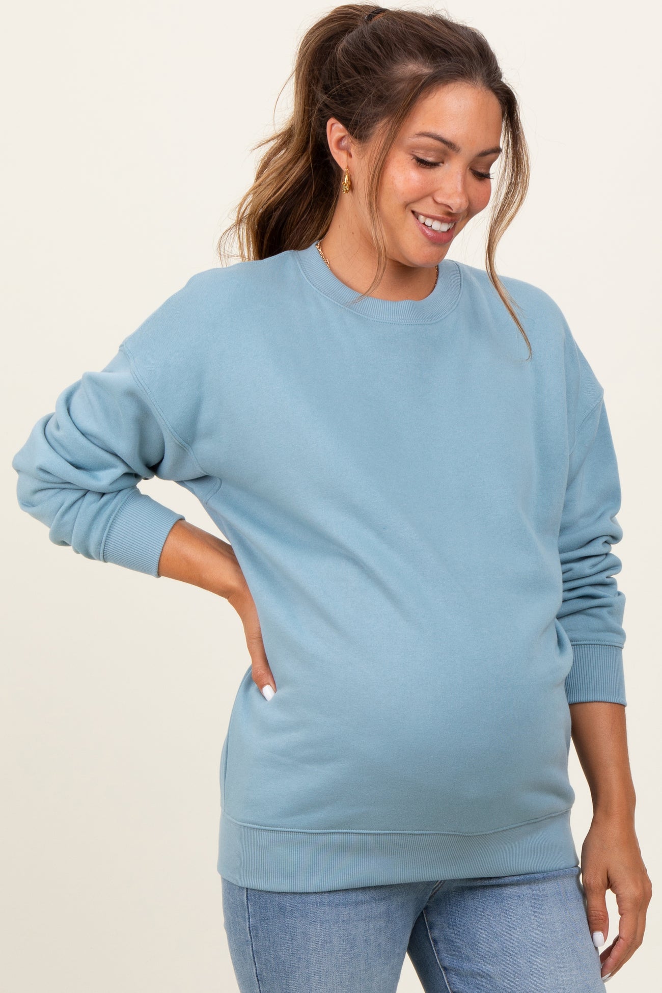 woman wearing a light blue maternity sweatshirt with a relaxed fit and a visible baby bump