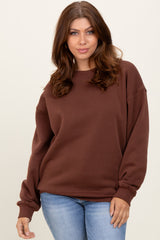 woman wearing a brown oversized sweatshirt paired with light blue jeans