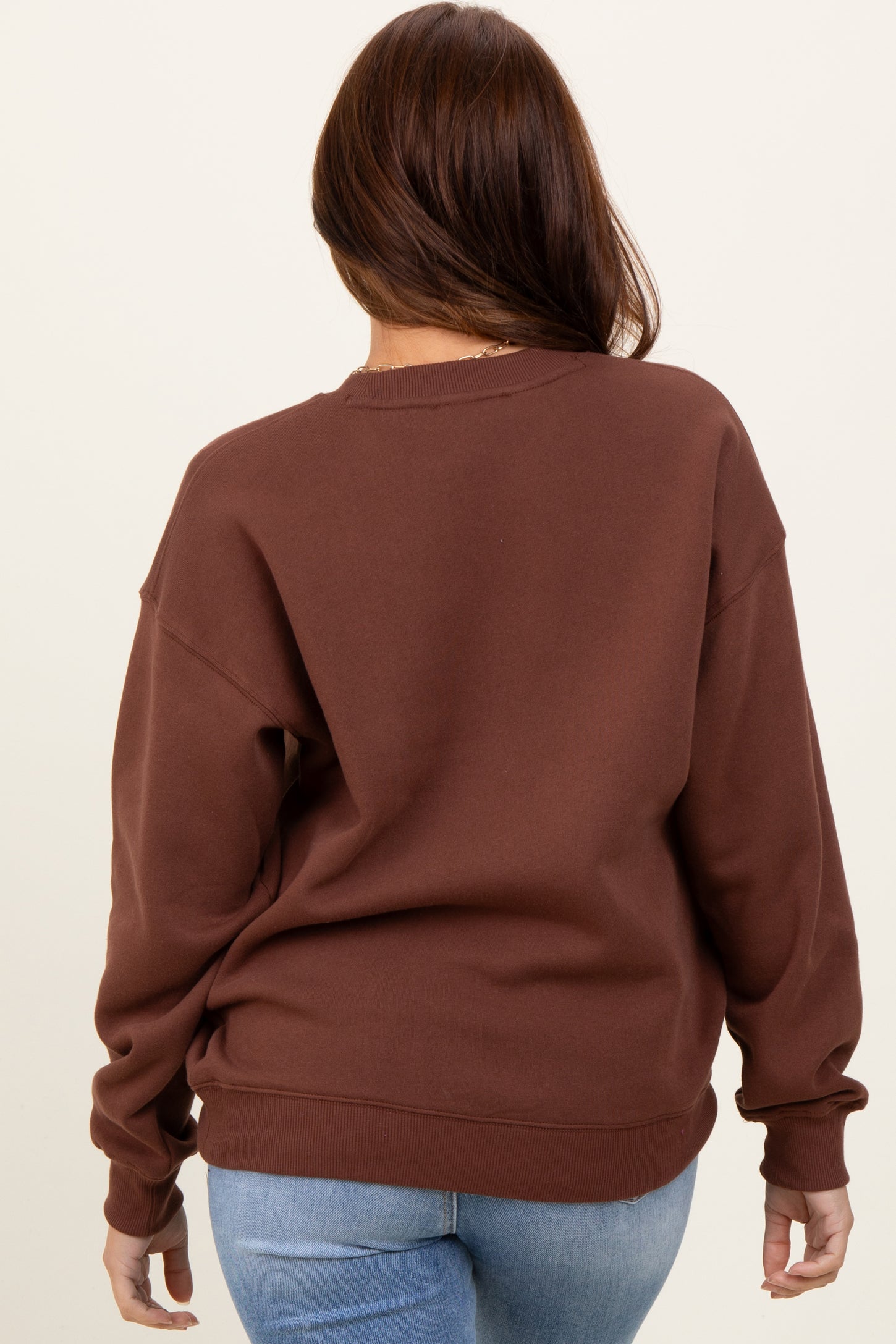 woman wearing a brown oversized sweatshirt with a relaxed fit and long sleeves