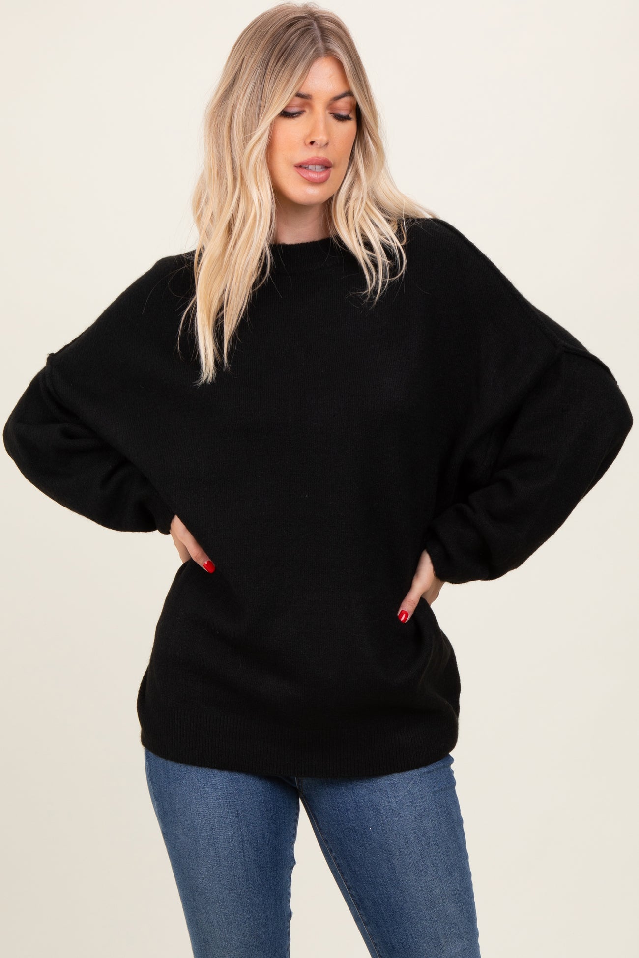 woman wearing an oversized black sweater with dropped shoulders and relaxed fit, paired with blue jeans
