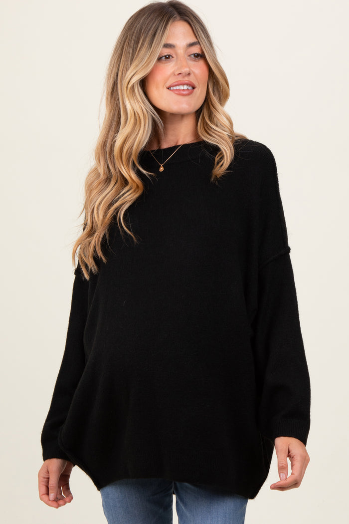 woman wearing a black oversized maternity sweater with a rounded hem and a visible baby bump