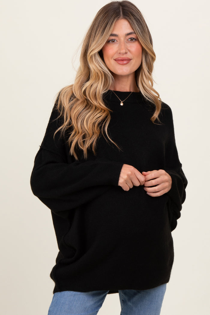 woman wearing a black oversized maternity sweater with long sleeves and a visible baby bump