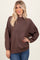 woman wearing a brown oversized knit sweater with dropped shoulders and long sleeves paired with blue jeans