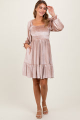 woman wearing a light pink smocked mini dress with puff sleeves and a tiered skirt, posing with one hand in her hair