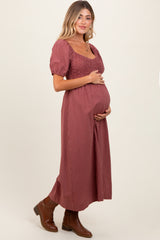 woman wearing a burgundy striped maternity dress with a square neckline and puff sleeves, holding her baby bump