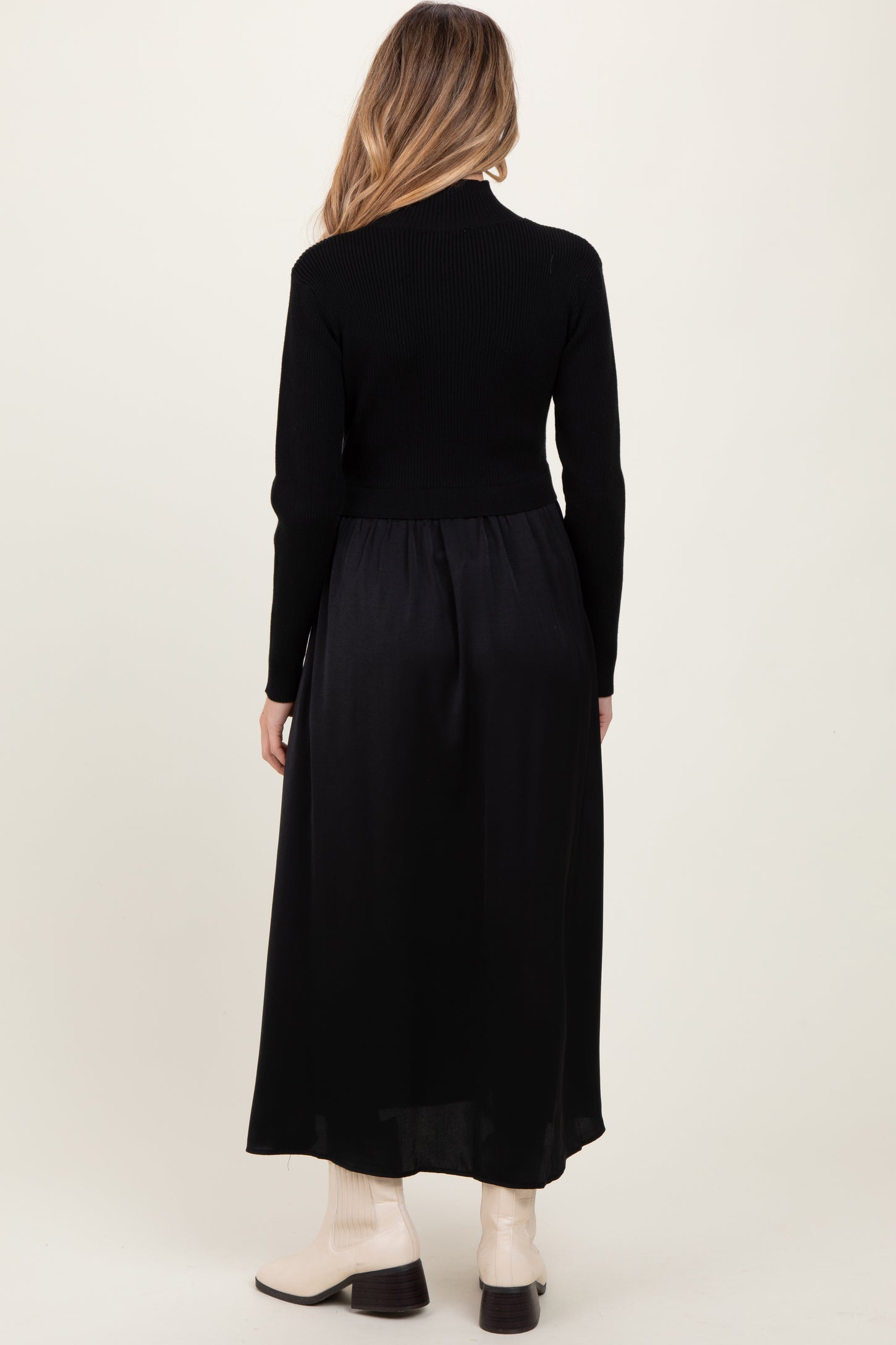 woman wearing a black maternity dress with a fitted top and a flowing skirt, showing off a baby bump from the back