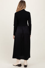 woman wearing a black maternity dress with a fitted top and a flowing skirt, showing off a baby bump from the back