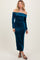 woman wearing a teal off-the-shoulder velvet maxi dress with long sleeves and a fitted silhouette