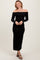 woman wearing a black off-the-shoulder maxi dress with long sleeves and a fitted silhouette