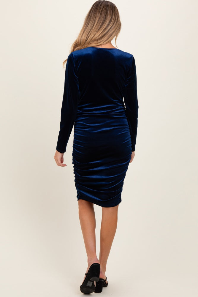 woman wearing a navy blue velvet long sleeve maternity dress with ruching detail on the back