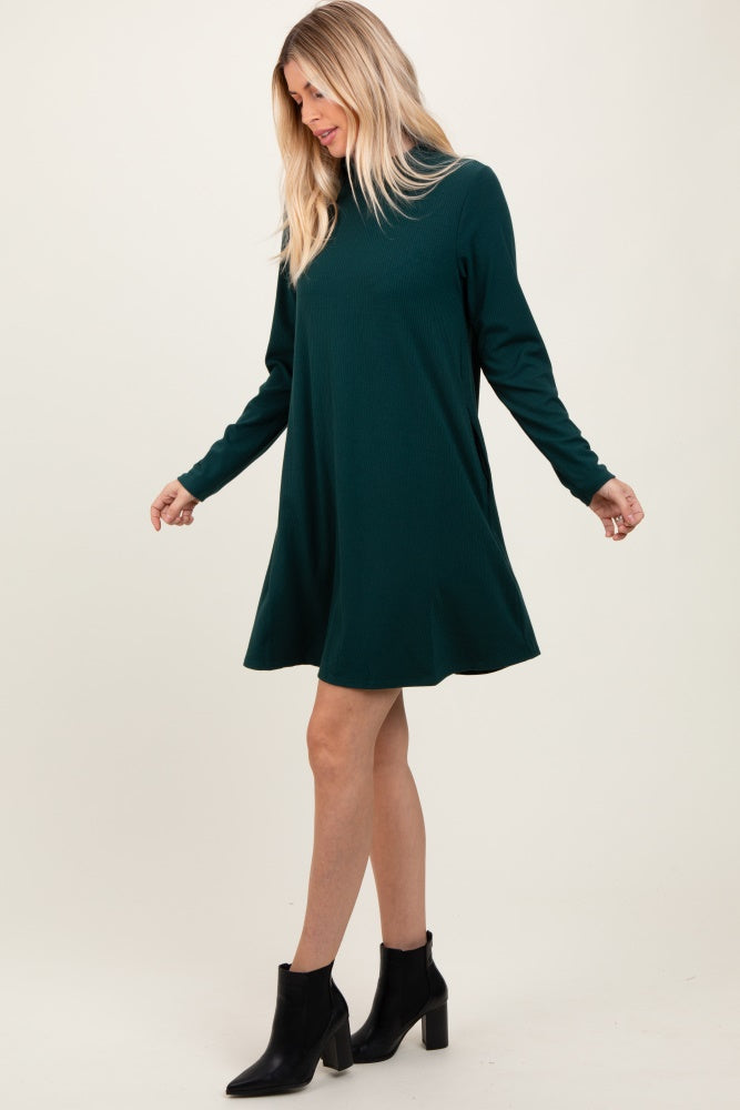 woman wearing a green long sleeve ribbed dress with a flared skirt and black ankle boots