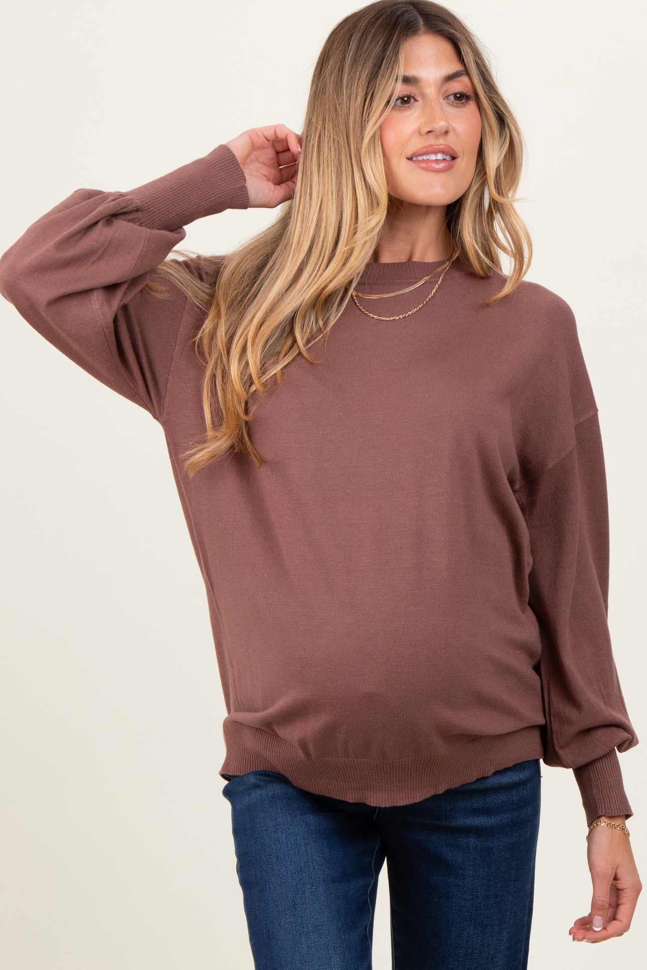 woman wearing a brown oversized maternity sweater with balloon sleeves and a visible baby bump.