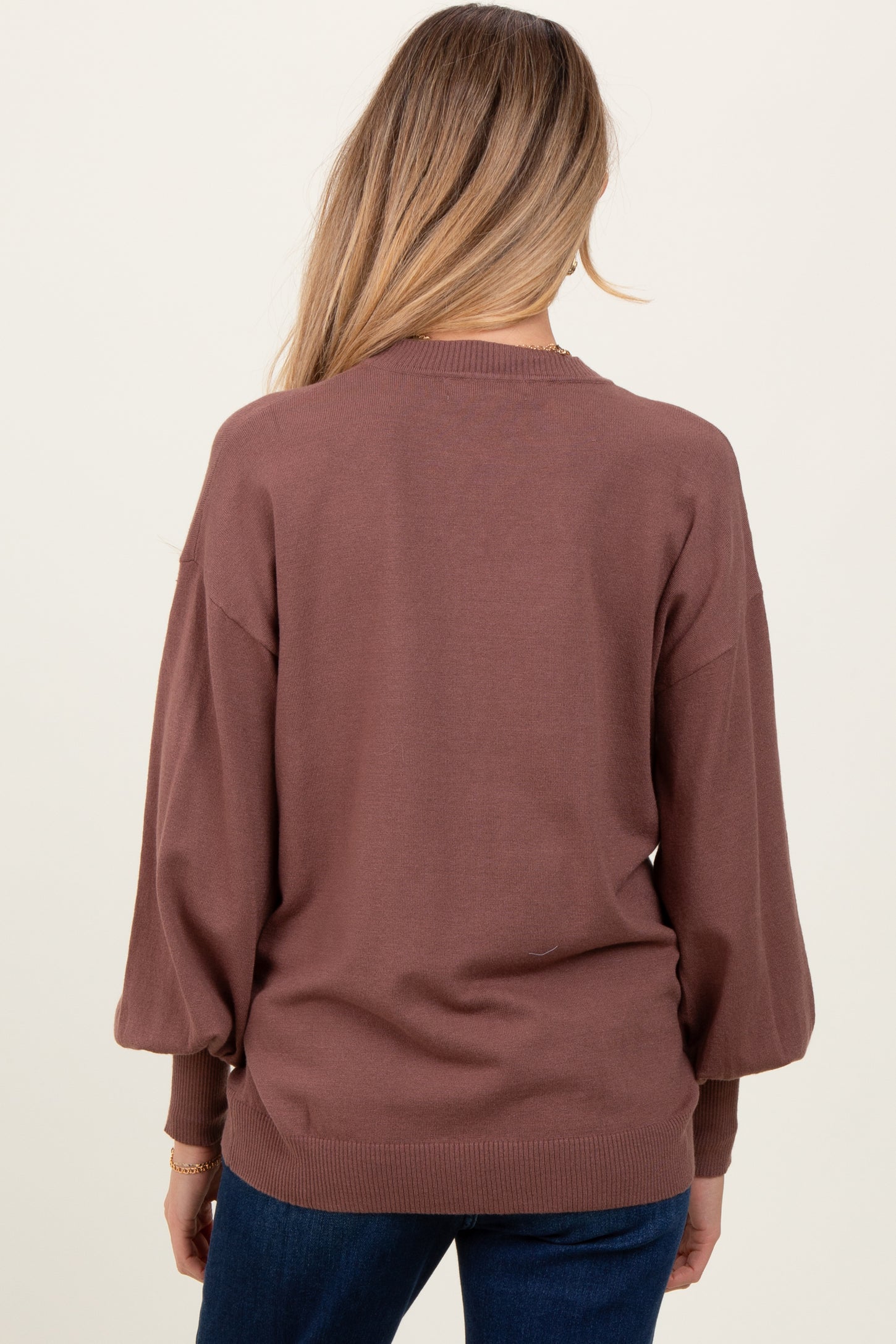 woman wearing a brown maternity sweater with puff sleeves, viewed from the back