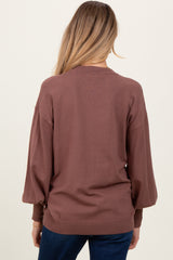 woman wearing a brown maternity sweater with puff sleeves, viewed from the back