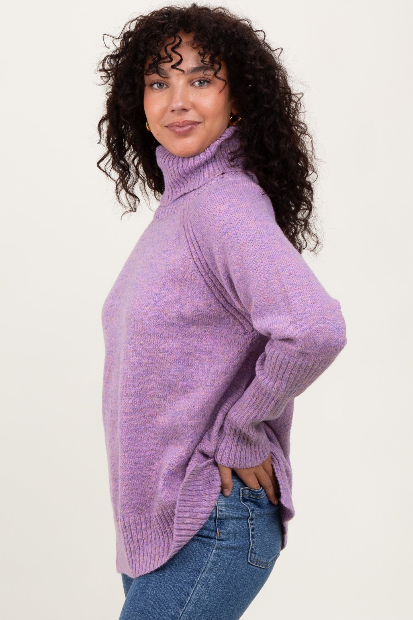 woman wearing a lavender turtleneck sweater with ribbed details and side slits, paired with blue jeans