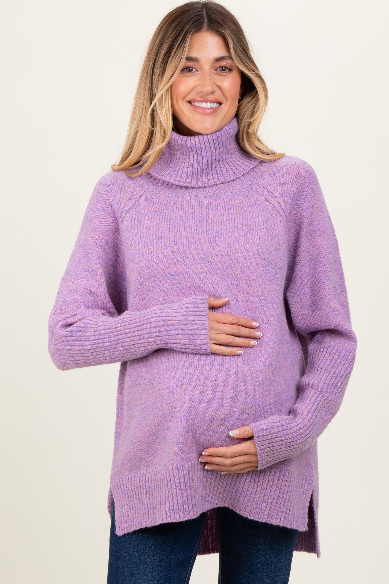 woman wearing a lavender turtleneck maternity sweater and cradling her baby bump