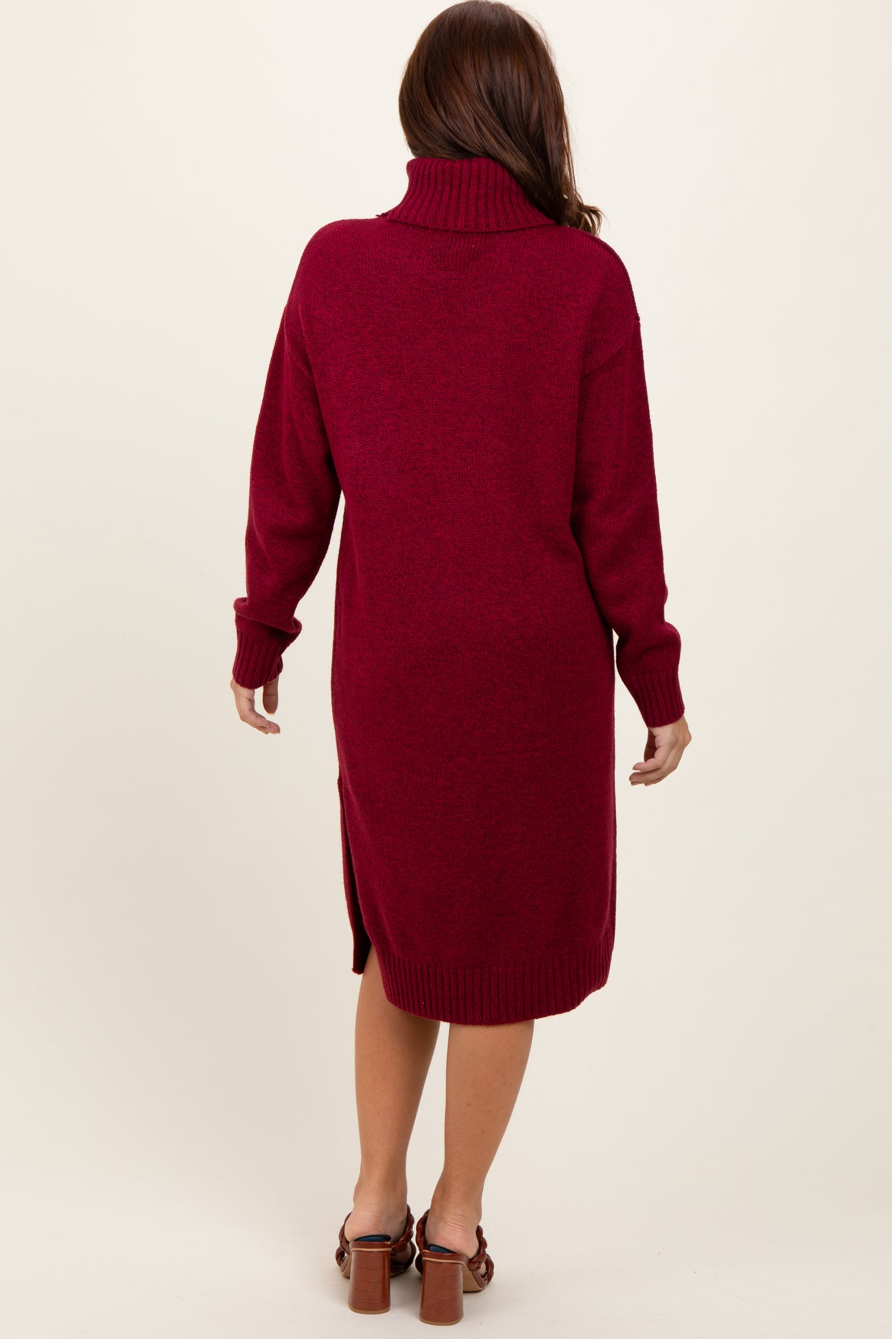 woman wearing a burgundy turtleneck sweater dress with side slits and long sleeves