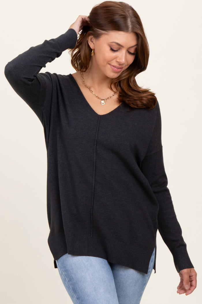 woman wearing a dark gray v-neck sweater with side slits and long sleeves, paired with light blue jeans
