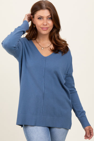 woman wearing a blue v-neck lightweight sweater with a relaxed fit and ribbed hem, posing with one hand in her hair