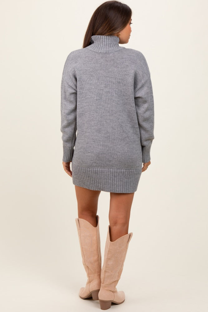 woman wearing a grey maternity sweater dress with a turtleneck and long sleeves, paired with tall beige boots