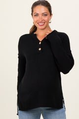 woman wearing a black maternity henley sweater with buttons and side slits, smiling at the camera