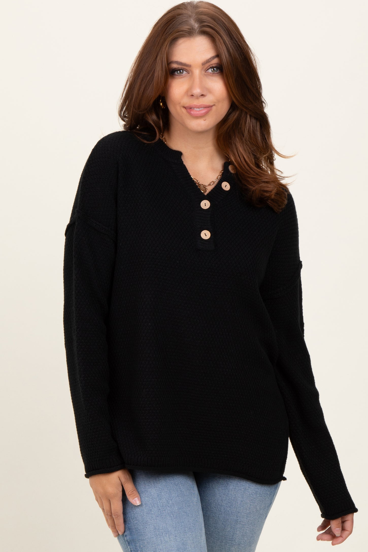 woman wearing a black long sleeve knit sweater with button details, styled with light blue jeans