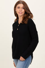 woman wearing a black long sleeve henley sweater with buttons and side slits, styled with light blue jeans
