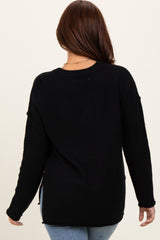 woman wearing a black waffle knit sweater with side slits, view from the back