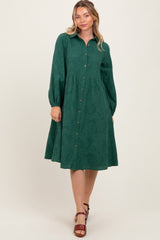woman wearing a dark green button-up dress with long sleeves and a flared skirt on a light background