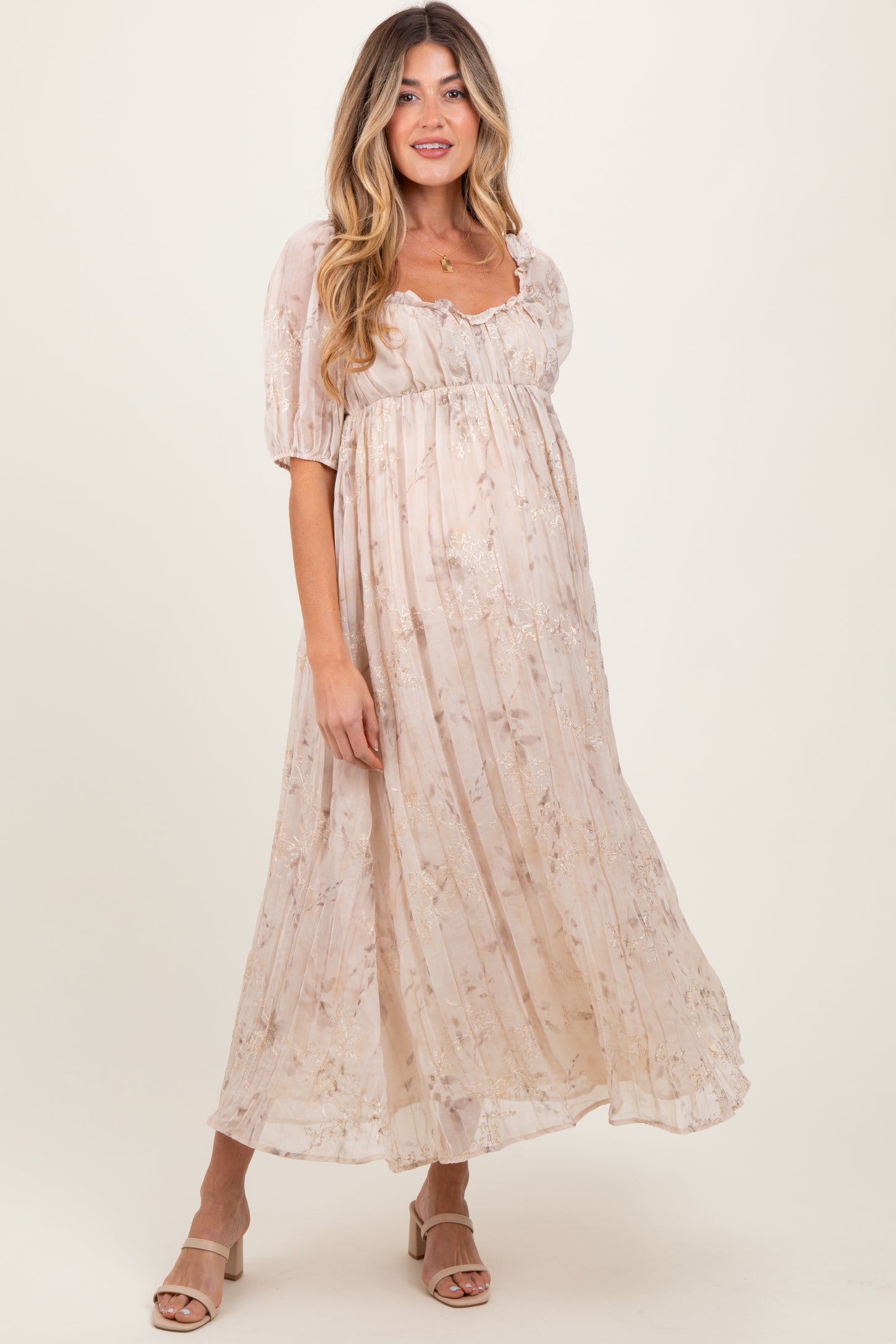 woman wearing a light floral maternity dress with short puff sleeves and a flowing silhouette