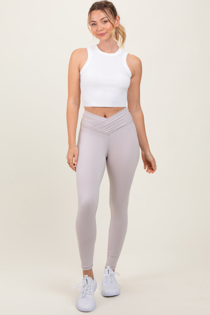 woman wearing a white cropped tank top and light gray high-waisted leggings