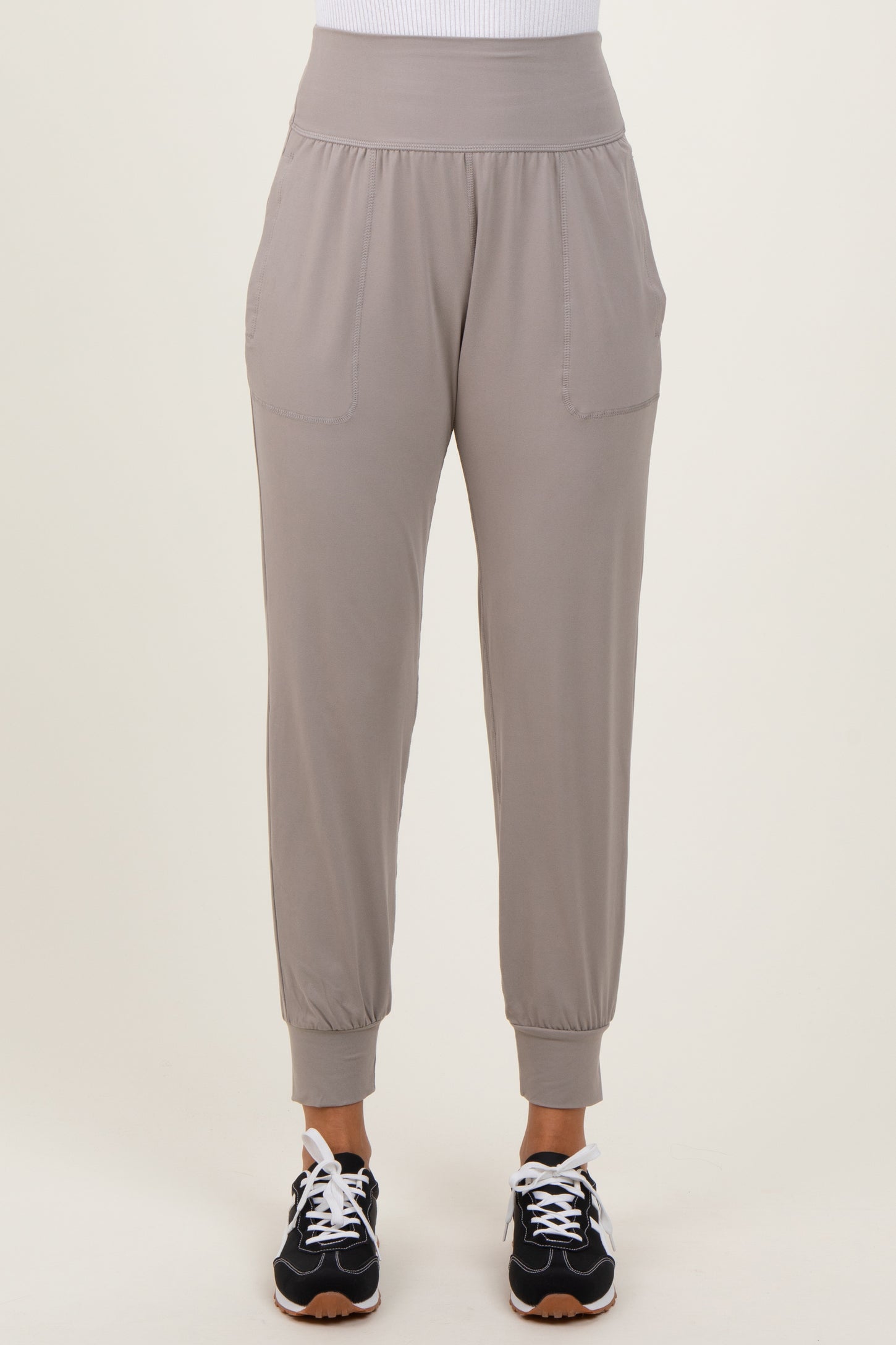 woman wearing light grey jogger pants with side pockets and elastic cuffs, paired with black athletic shoes