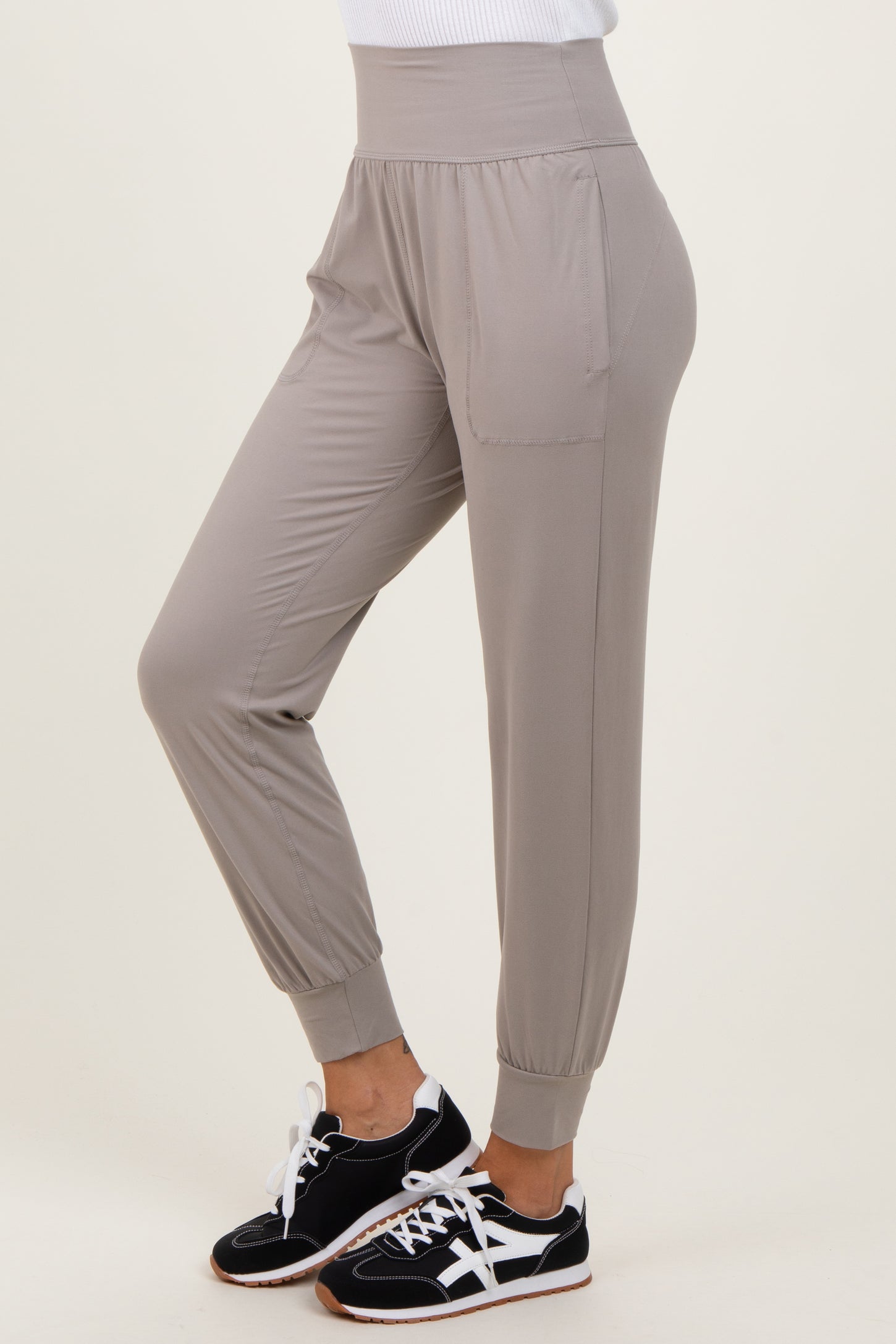 woman wearing light grey casual jogger pants with side pockets and elastic cuffs, paired with black sneakers