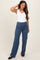 woman wearing a white tank top and blue maternity yoga pants with a high waistband and wide legs