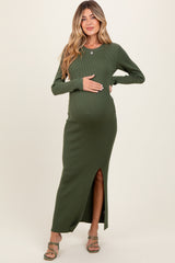 woman wearing a dark green ribbed maternity maxi dress with a side slit and holding her baby bump