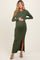 woman wearing a dark green ribbed maternity maxi dress with a side slit and holding her baby bump