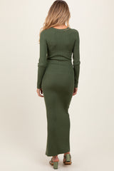 woman wearing a dark green ribbed maternity maxi dress with long sleeves and a fitted silhouette