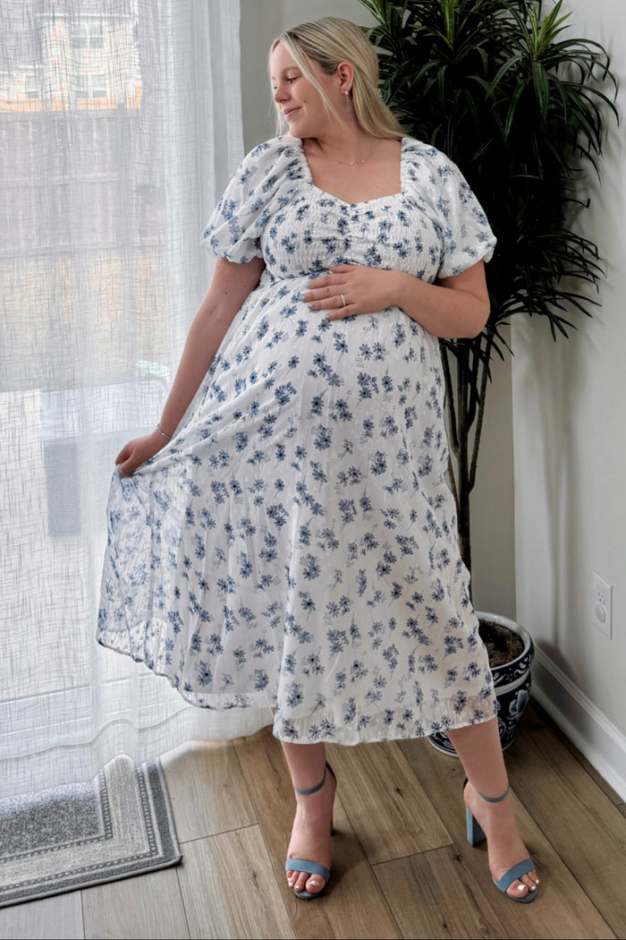 woman wearing a white floral maternity dress with a square neckline and puff sleeves, showing her baby bump