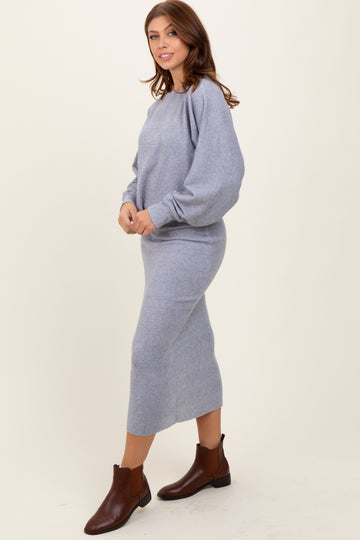 woman wearing a light gray sweater dress with balloon sleeves and brown ankle boots