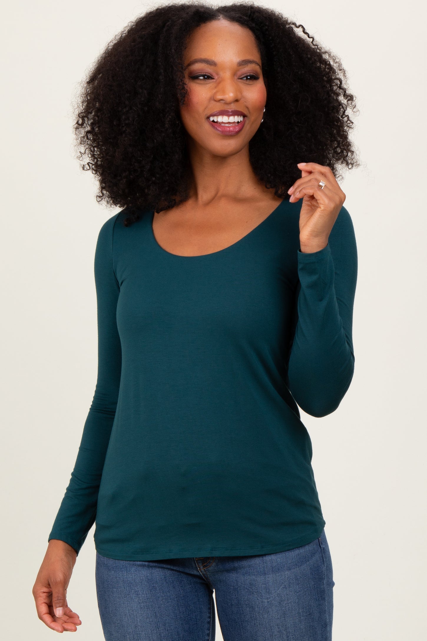 woman wearing a teal long sleeve scoop neck top paired with blue jeans