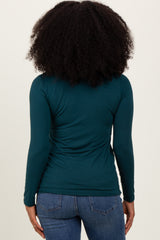 woman wearing a teal long sleeve top with a fitted silhouette, viewed from the back, paired with blue jeans