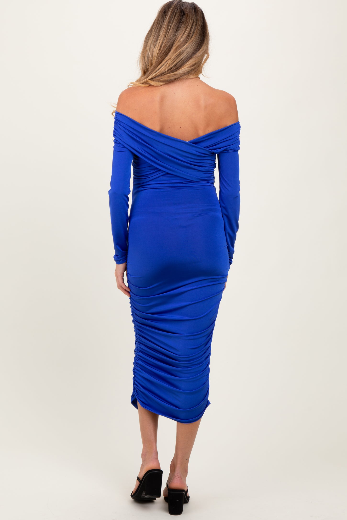 woman wearing a royal blue off-the-shoulder maternity dress with ruching details along the back and hips