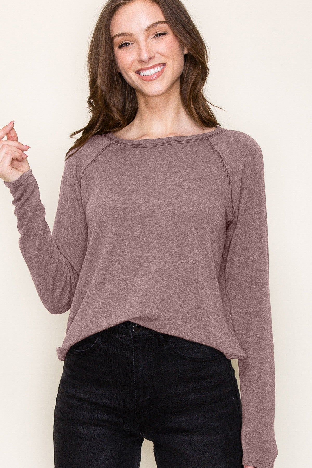 woman wearing a mauve long sleeve top with a relaxed fit and round neckline paired with black jeans