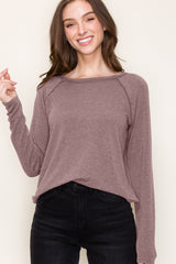 woman wearing a mauve long sleeve top with a relaxed fit and round neckline paired with black jeans