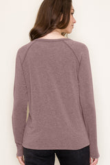 woman wearing a mauve long sleeve top with a relaxed fit and raglan sleeves, viewed from the back