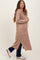 woman wearing a tan maternity cardigan with pockets and a side slit, holding her baby bump while smiling