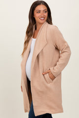 woman wearing a beige maternity wrap coat with pockets and a visible baby bump