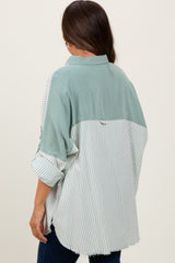 woman wearing a green and white striped maternity shirt with a relaxed fit and rolled-up sleeves